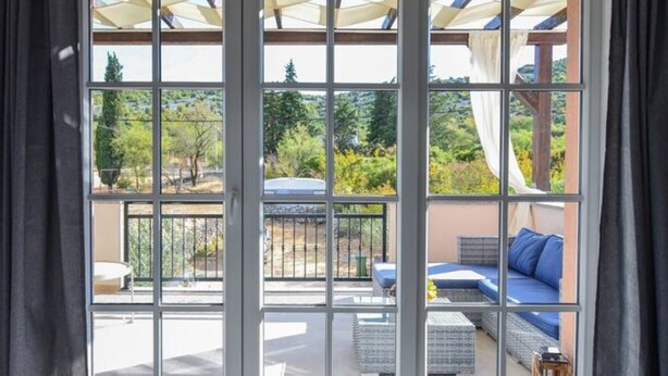 A room with a large sliding glass door leading to an outdoor patio area with a sofa and cushions. - Apartment Villa Troskot (Pirovac)