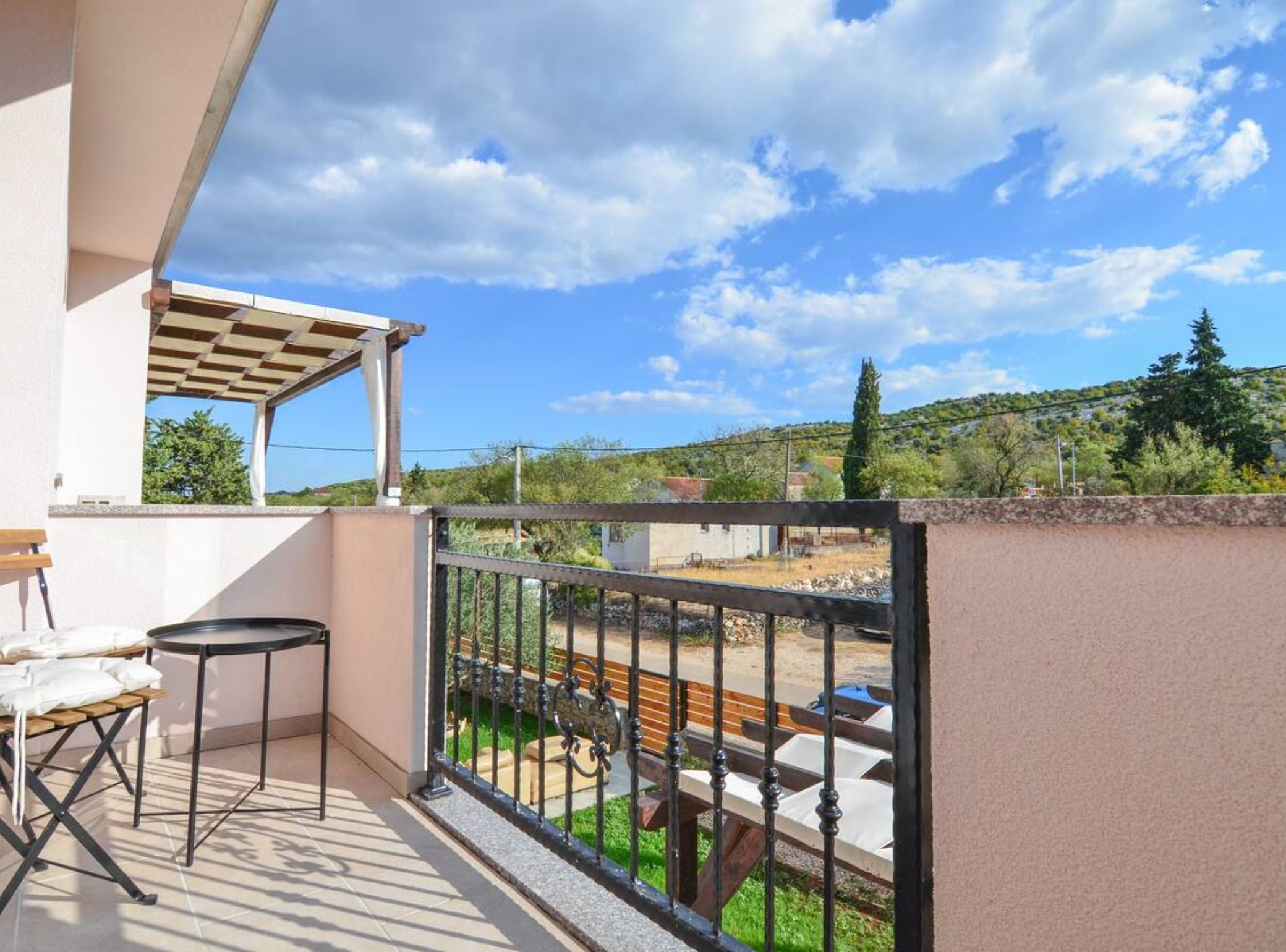 Ein Balkon mit Blick auf eine grüne Landschaft und ferne Hügel.