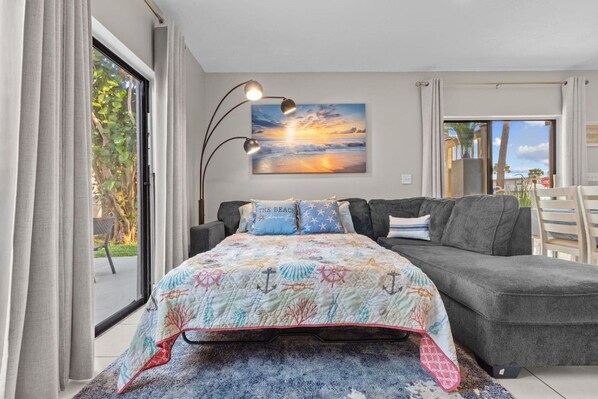 Un dormitorio con cama, sofá, un cuadro y vistas al exterior.