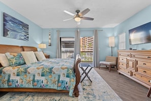 A bedroom with a bed, dresser, chair, and a ceiling fan.