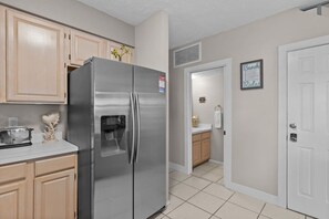 Una cocina con un refrigerador de acero inoxidable, armarios de madera, una encimera con un tostador y un lavabo.