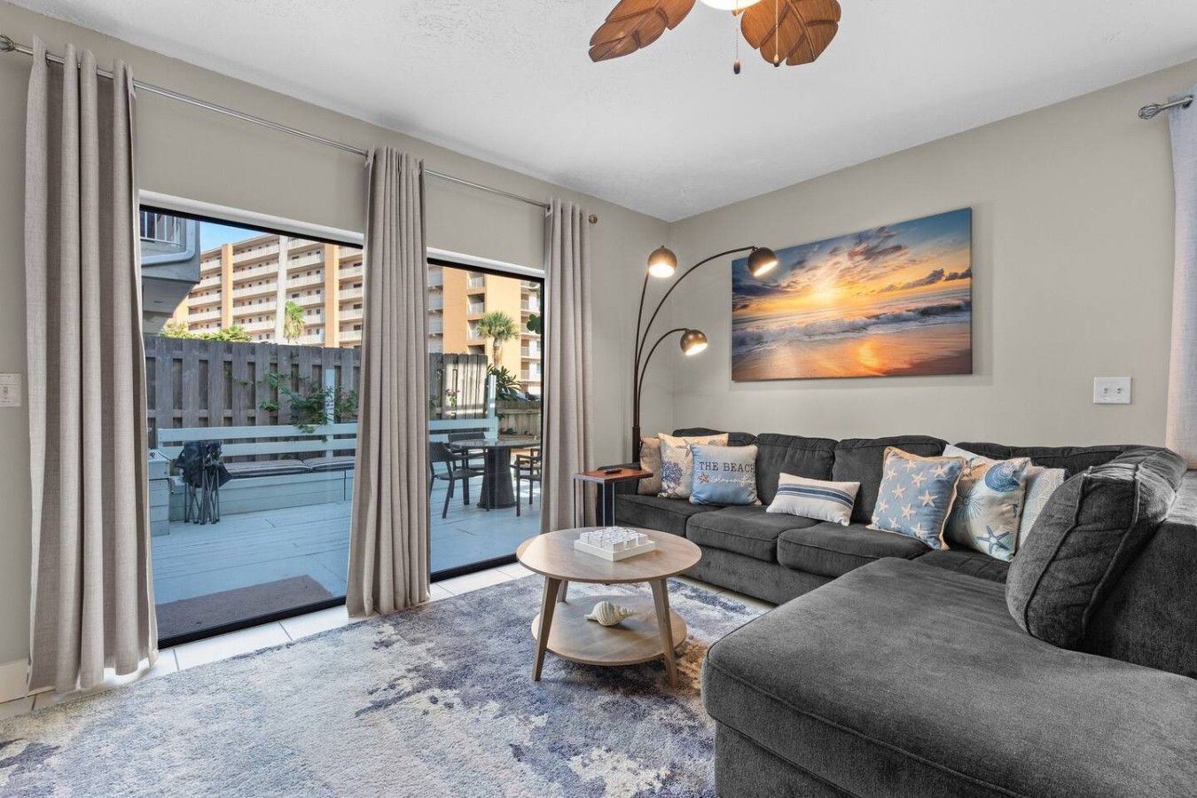 A modern living room with a grey sofa, a round coffee table, and a painting of a sunset.