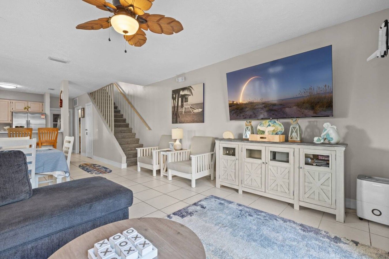 A living room with a sofa, a coffee table, a fireplace, a staircase, and a dining area.