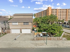 Un immeuble résidentiel doté d’un garage, d’une allée et d’un petit jardin agrémenté d’un arbre et d’une clôture.