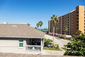 A hotel with a balcony, a parking area, and a view of the ocean.