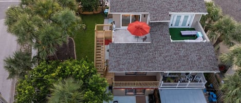Una propiedad residencial con una casa de dos pisos, un porche cubierto y un patio cercado.