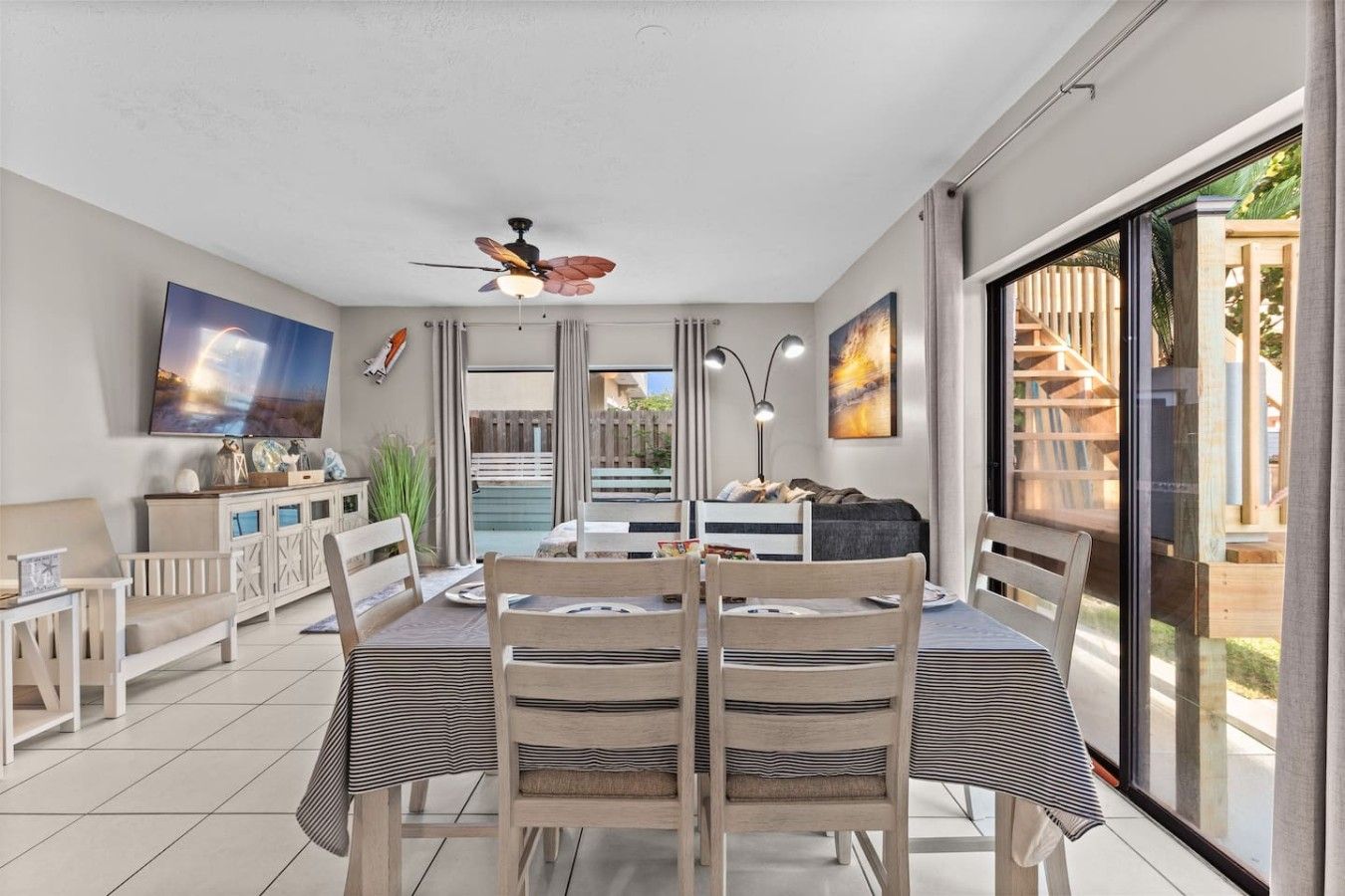 A dining area with a table and chairs, a ceiling fan, and a view of the outdoors.