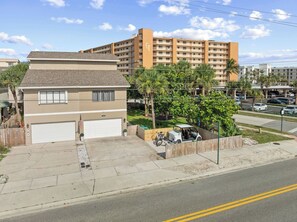Una propiedad residencial con un garaje, una casa pequeña y un edificio de apartamentos grande al fondo.