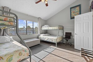Une chambre avec un lit superposé, un bureau, une chaise et une porte.