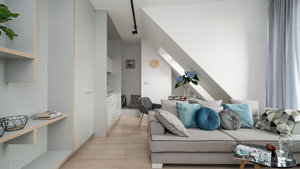 A modern living room with a grey sofa, a coffee table, and a staircase leading to an upper level.