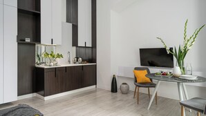 A modern kitchen with dark wood cabinets, a white countertop, and a built-in TV.