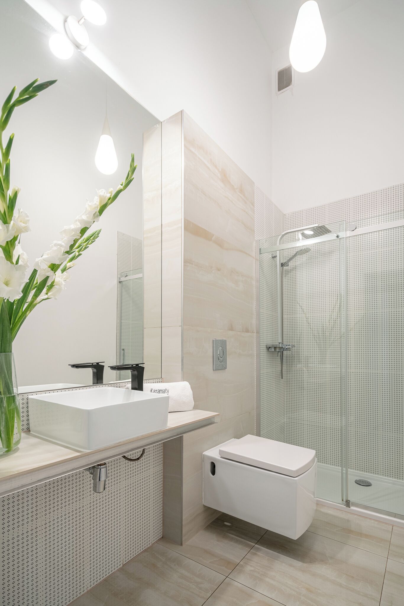 A modern bathroom with a white sink, a toilet, and a glass shower enclosure.