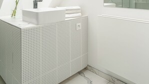 A modern bathroom with a skylight, a white sink, and a large mirror.