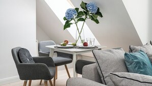 A modern dining area with a round table, gray chairs, and a vase with blue flowers.