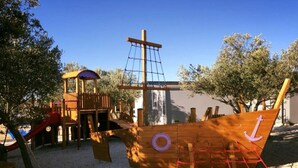 A playground with a ship-shaped play structure, including a slide and climbing net. - Gabrijela House (Pirovac)