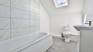 Ein modernes Badezimmer mit einer freistehenden Badewanne, einer Toilette und einem Waschbecken.