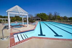 Relax by the pool under a shaded pergola, surrounded by a low wall and a clear pool with lane markings.