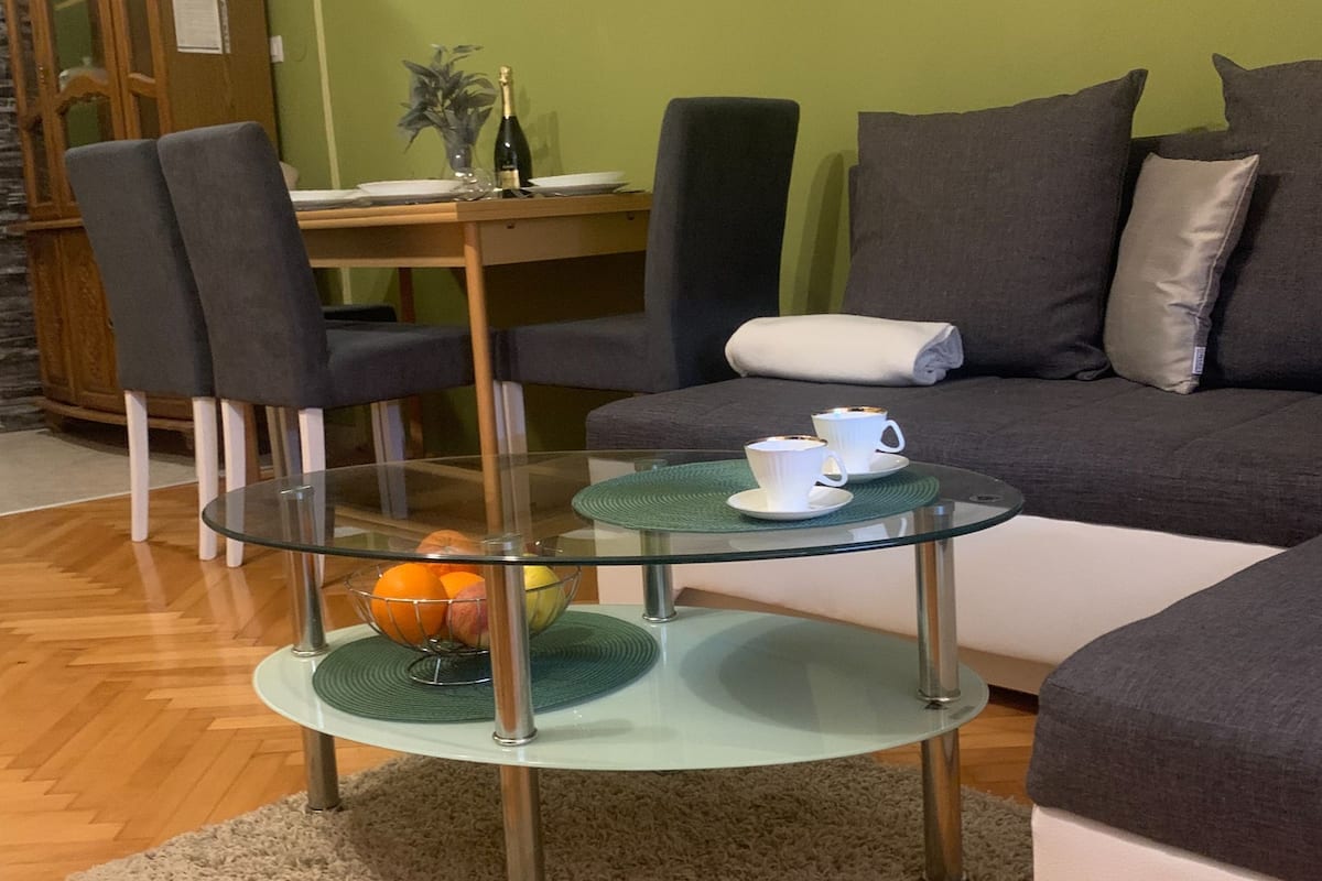 A modern living room with a glass coffee table, a sofa, and a dining area with chairs and a table.