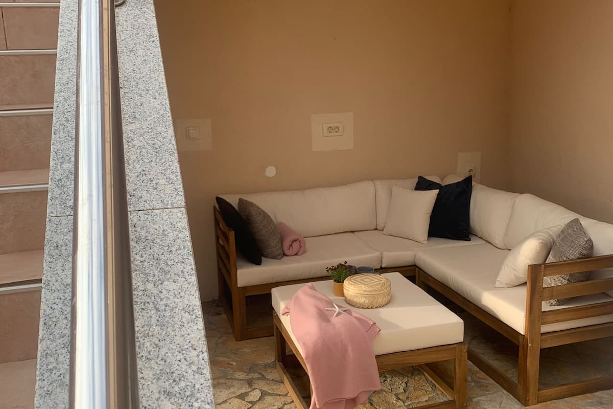 A cozy living room with a beige sectional sofa, a wooden coffee table, and a pink throw blanket.