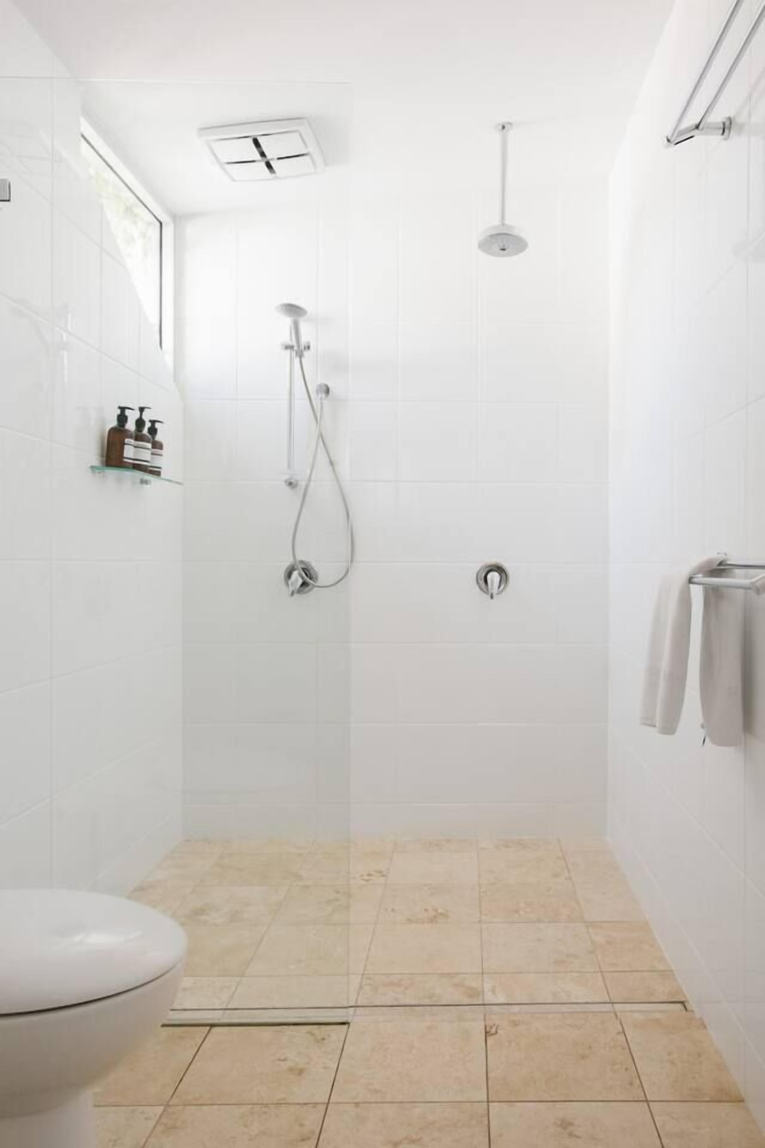 Baño con ducha, inodoro y barra para toallas.