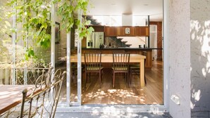 A modern kitchen with a wooden island, a dining area with chairs, and a glass door leading to a patio with a metal table and chairs.