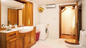 Un baño pequeño con armarios de madera, lavadora e inodoro.