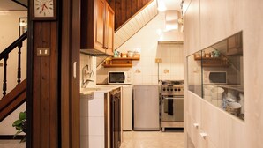 Una cocina con armarios de madera, microondas, estufa y refrigerador.