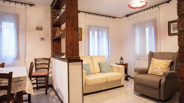 Una sala acogedora con sofá, sillón y mesa de comedor.