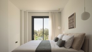 Una camera da letto moderna con un letto grande, vista attraverso una porta scorrevole, una lampada a sospensione e un elemento decorativo a parete.