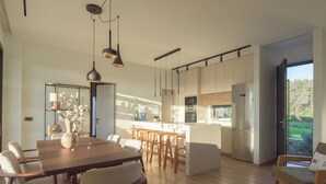 Una cucina moderna con isola centrale, sedie in legno e luci a sospensione.