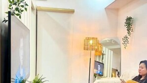 Un salon avec un téléviseur, un canapé, une table basse et un lampadaire.