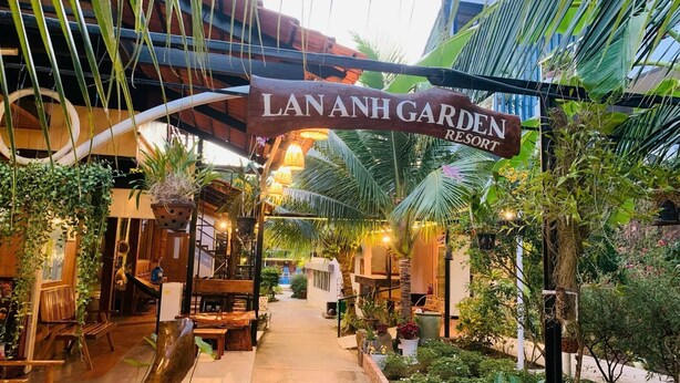A pathway leading to Lananh Garden Resort, surrounded by lush greenery and wooden structures. - Lan Anh Garden Resort (Phu Quoc)