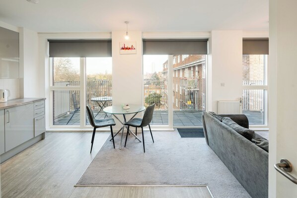Enjoy a spacious apartment with a dining area, comfortable sofa, and kitchenette, offering a city view.