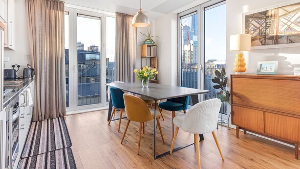 A modern kitchen with a dining area, large windows, and a city view. - Perfectly Located Comfy 1-Bed in London Bridge - Pass the Keys (London)