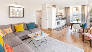 A modern apartment with a grey sofa, a coffee table, and a dining area with a table and chairs. - Perfectly Located Comfy 1-Bed in London Bridge - Pass the Keys (London)