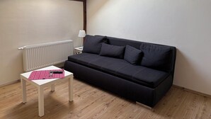 A small, modern room with a black sofa, a white table, and a radiator.