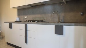 Eine moderne Küche mit weißen Schränken, einer grauen Arbeitsplatte und einer Edelstahl-Dunstabzugshaube.