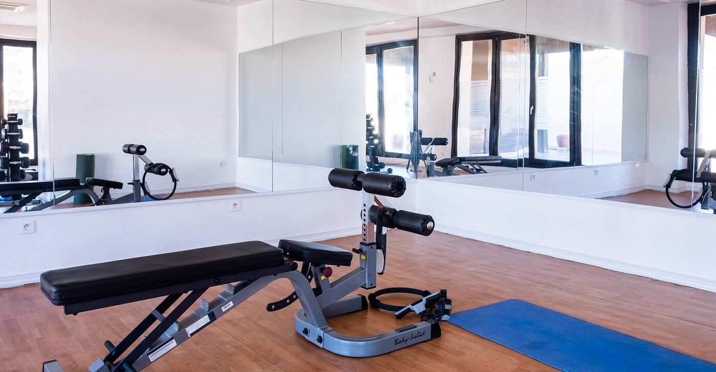 A gym with a bench, weight machine, and a mirror.