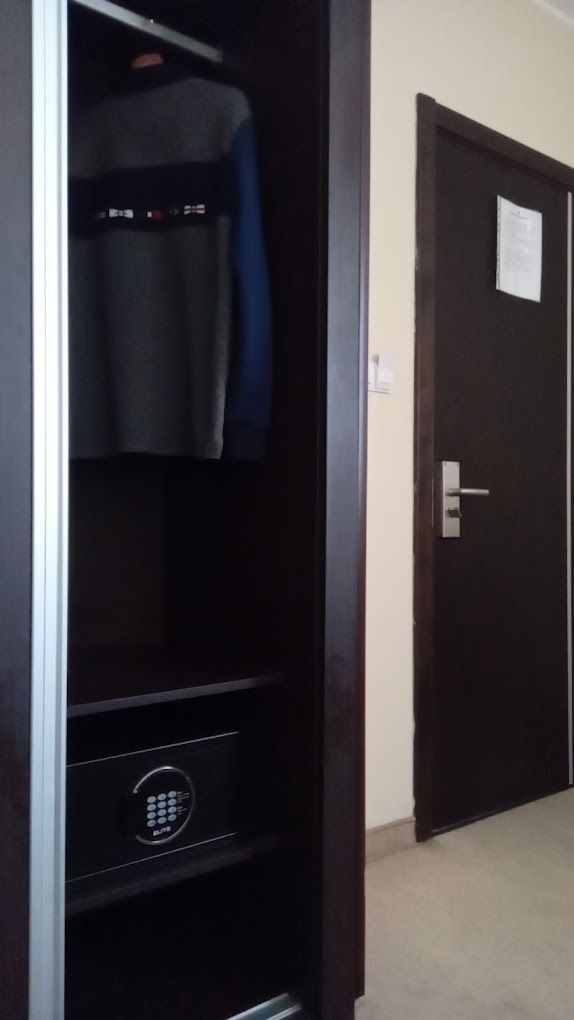 Une armoire en bois sombre, dotée d’un coffre-fort intégré et d’une tringle pour suspendre les vêtements.
