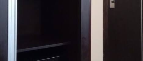 Une armoire en bois sombre, dotée d’un coffre-fort intégré et d’une tringle pour suspendre les vêtements.