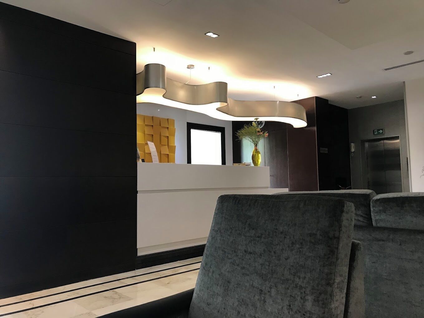 A modern reception area with a reception desk, a wall-mounted clock, and a vase with flowers.