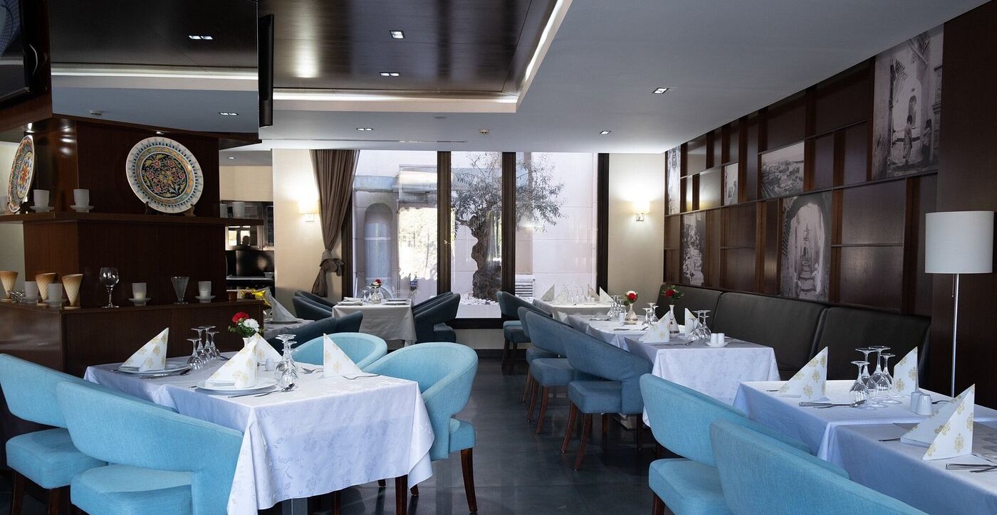 Un restaurante con mesas redondas, sillas azules y vistas al exterior.