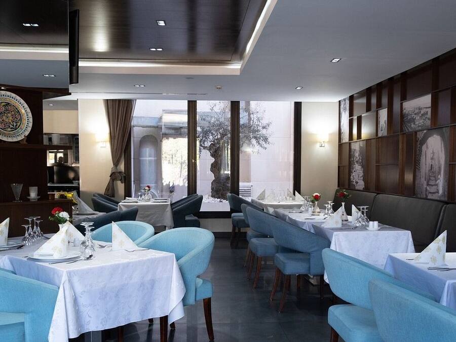 Un restaurante con mesas redondas, sillas azules y vistas al exterior.