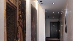 Un corridoio con pavimento in legno, un quadro grande a sinistra e una porta in fondo.