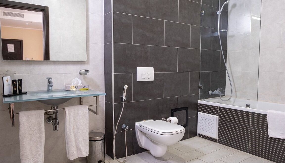 A modern bathroom with a glass sink, a toilet, and a bathtub.