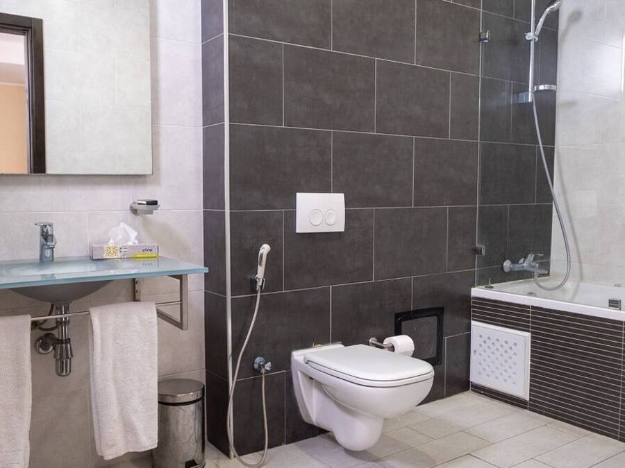 Un baño moderno con un lavamanos de vidrio, un inodoro y una bañera.