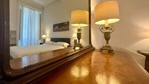 A hotel room with a large mirror, two bedside lamps, a bed, a nightstand, and a painting on the wall. - Casa Milano Classic Elegance with Balcony (Milan)