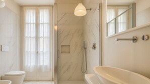 A modern bathroom with a glass-enclosed shower, a freestanding bathtub, and a toilet. - Casa Milano Classic Elegance with Balcony (Milan)