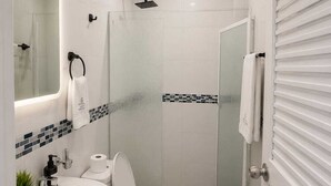 A bathroom with a toilet, sink, shower, and a mirror. - ULTIMO DEL SEMANA (San Andrés)