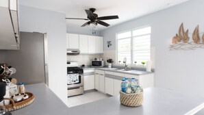 Una cocina moderna con armarios blancos, microondas, horno y ventilador de techo.